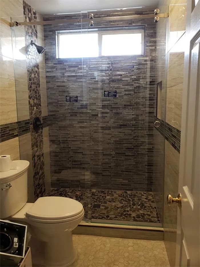 Small bathroom with a glass-enclosed tiled shower and a toilet in the foreground.
