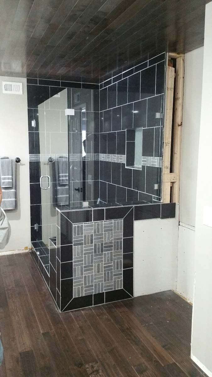 Small dark-tiled fireplace or stove alcove in a room with wood floors and a white door.