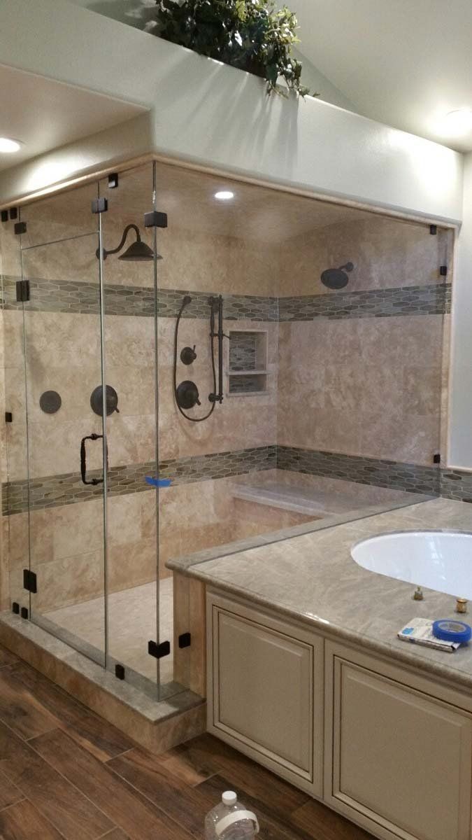 Spacious bathroom with glass walk-in shower, beige tile, and double vanity countertop