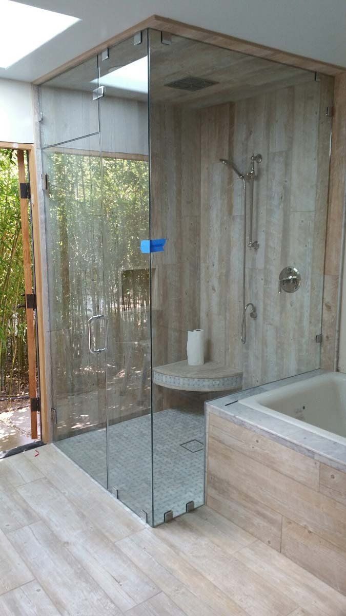 Modern bathroom with glass shower, wood-look tile, and a soaking tub by the wall