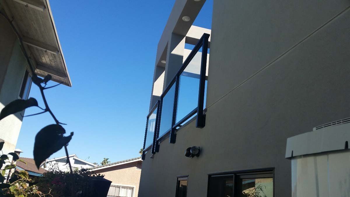 Gray house exterior with dark blue window awnings against a clear blue sky