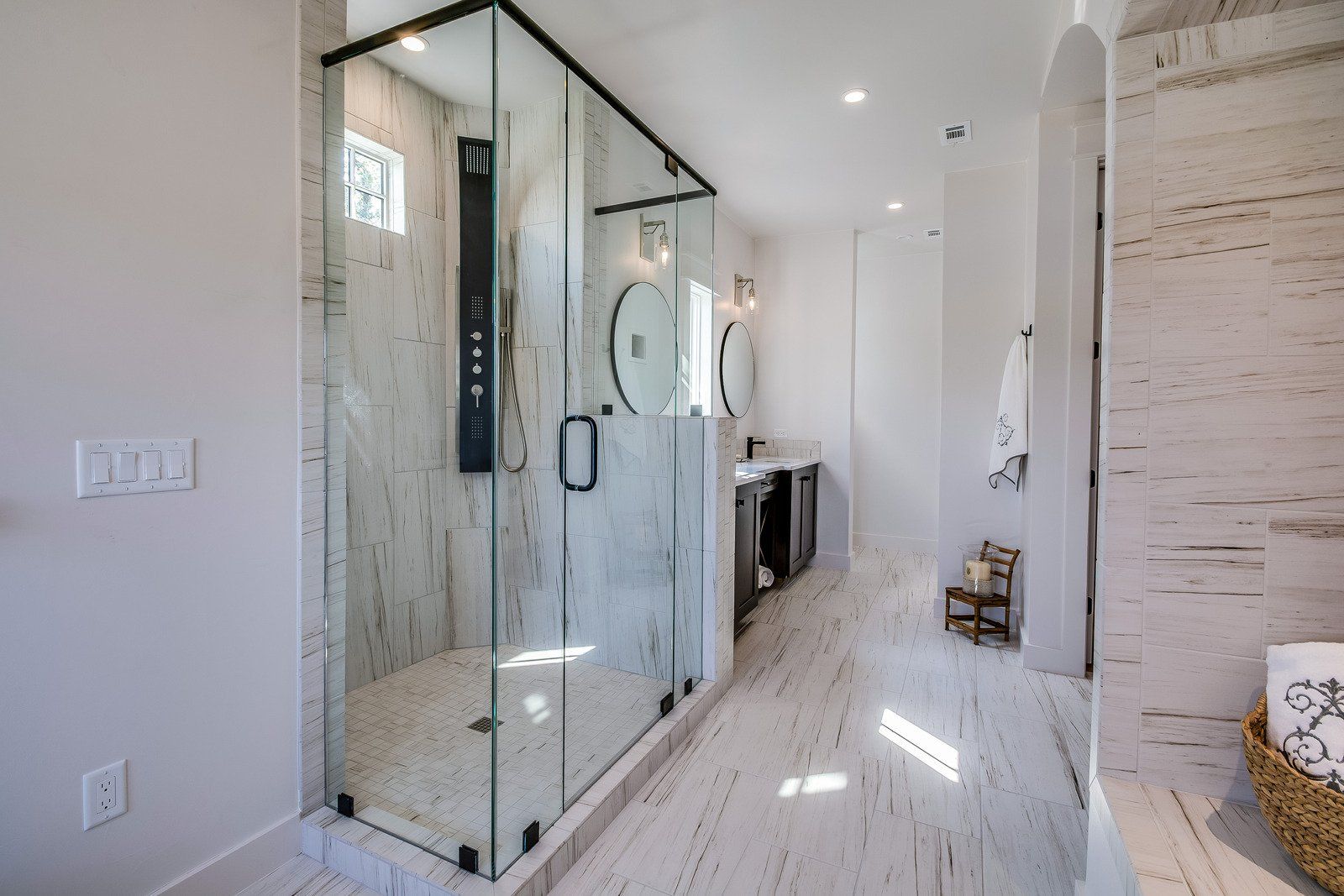 Modern bathroom with a glass shower, vanity, and patterned white walls and floor.