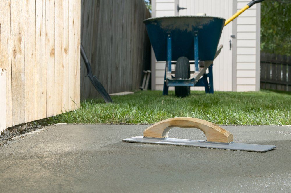 A Freshly Poured Concrete Surface With a Trowel in a Backyard Near a Fence — Comet Concreting in Drayton, QLD