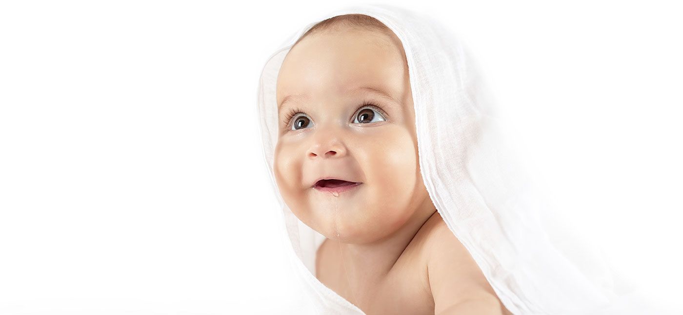 Smiling baby wrapped in a white towel on a white background.