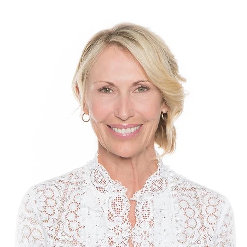 Smiling blonde woman in a white lace blouse against a white background
