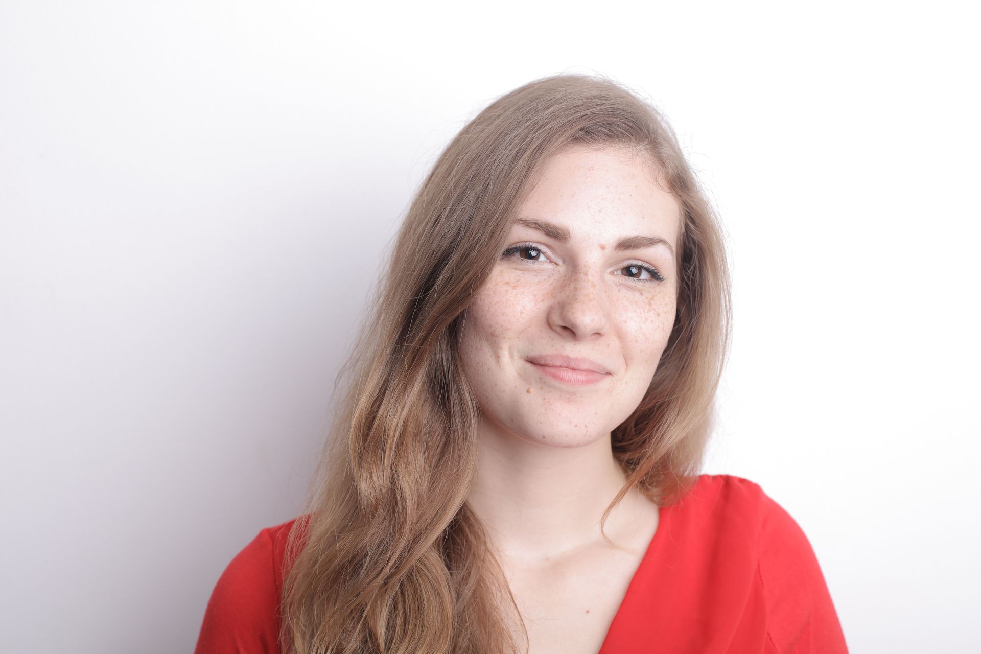 Smiling woman with long hair wearing a red top against a light background