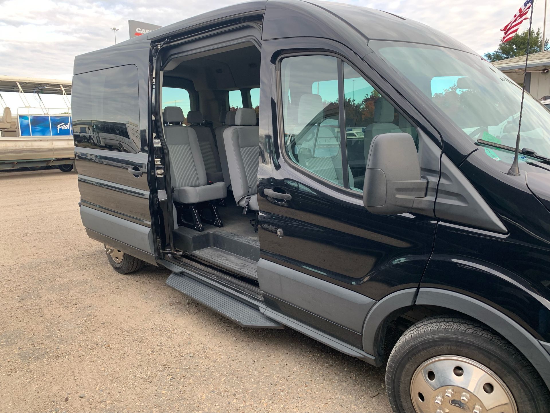 A black van with the doors open is parked in a dirt lot.