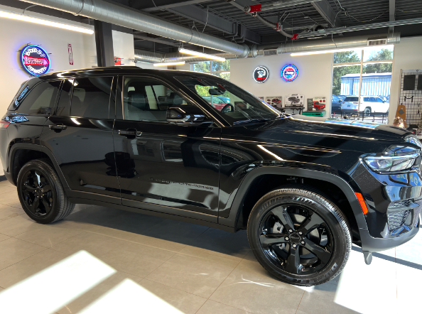 A black jeep grand cherokee is parked in a showroom.