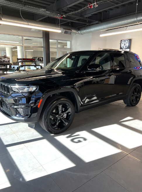 A black jeep grand cherokee is parked in a showroom.