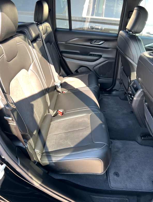 The back seats of a black jeep grand cherokee are empty.