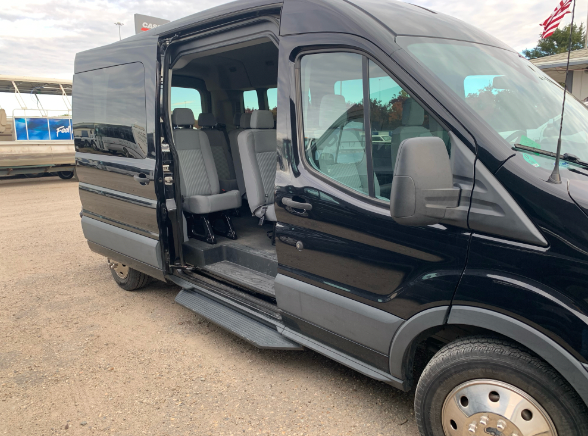 A black van with the door open is parked in a parking lot.