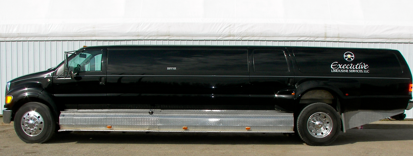 A black limousine is parked in front of a building