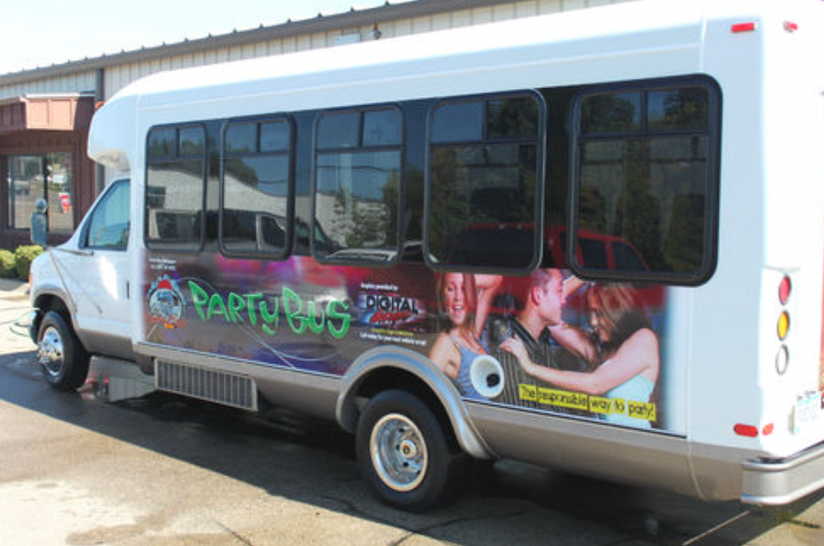A white party bus is parked in front of a building