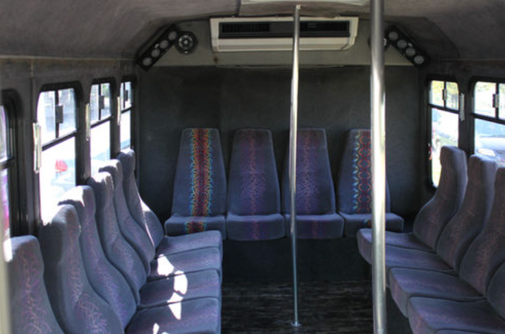 The inside of a bus with purple seats and poles