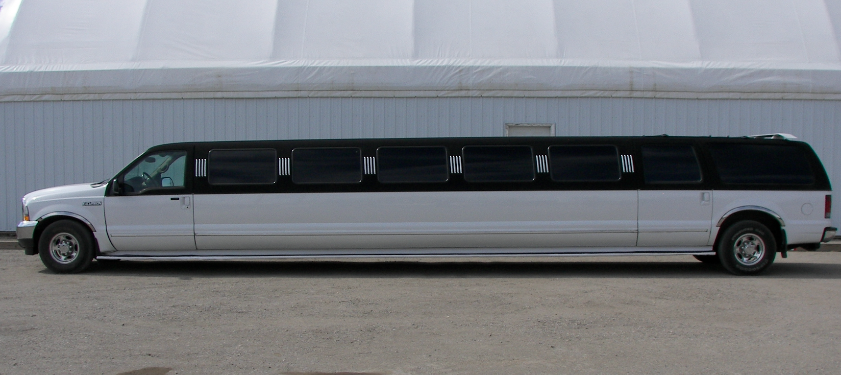 A long white limousine is parked in front of a building.