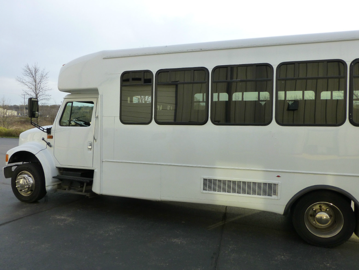 A white bus is parked in a parking lot.