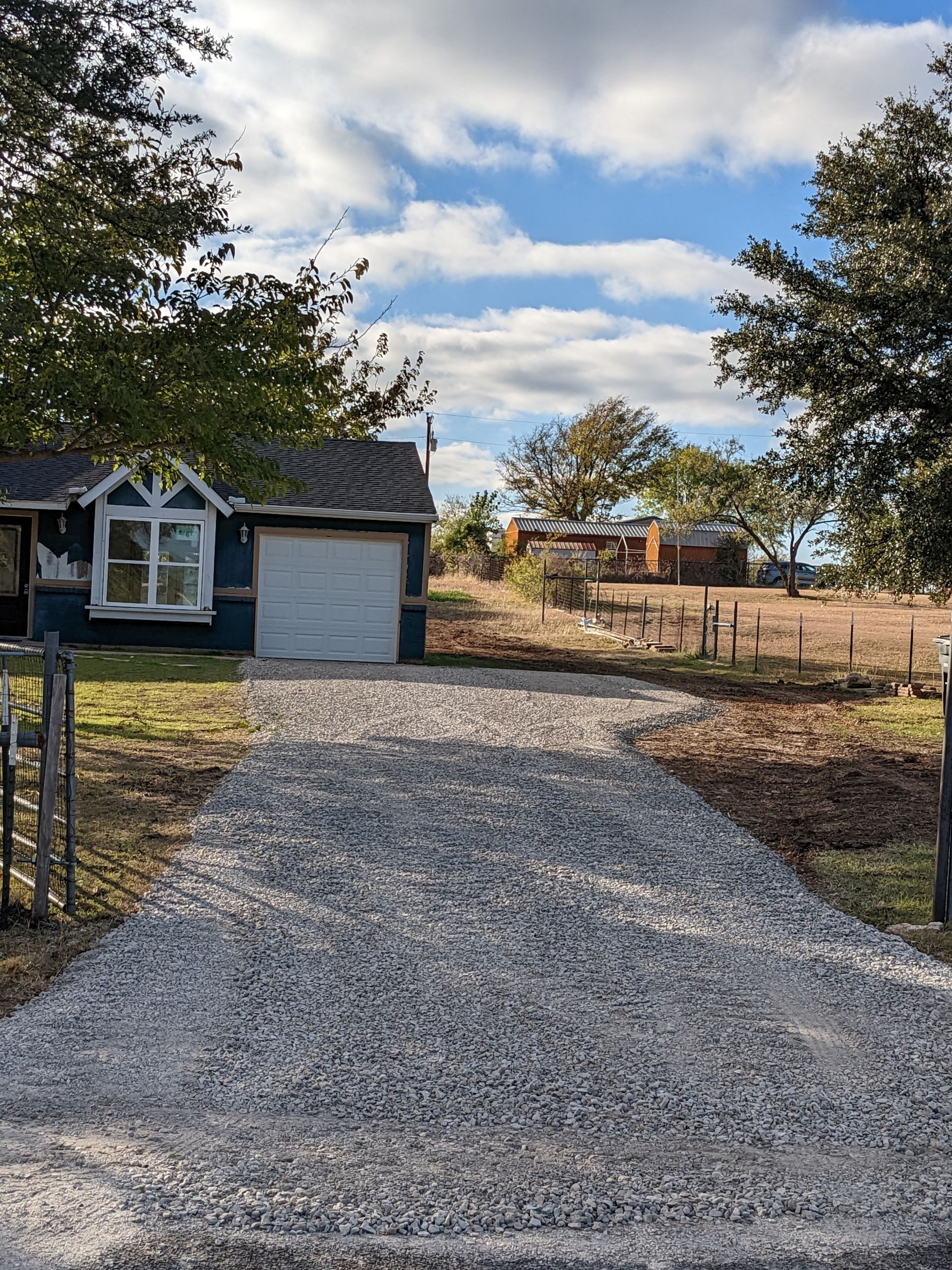 A gravel driveway leading to a house with a garage