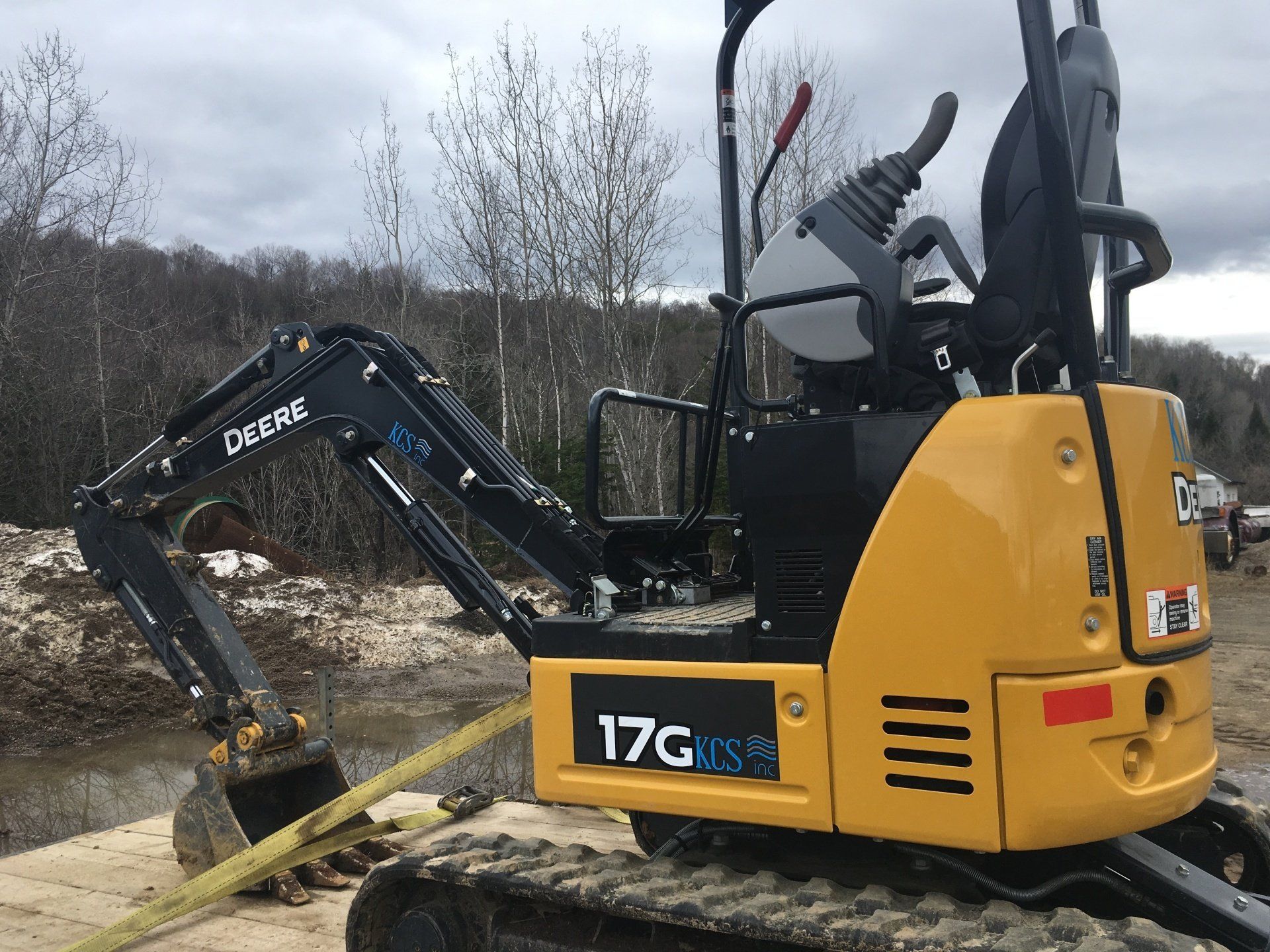 Une petite excavatrice jaune est garée sur un chemin de terre.