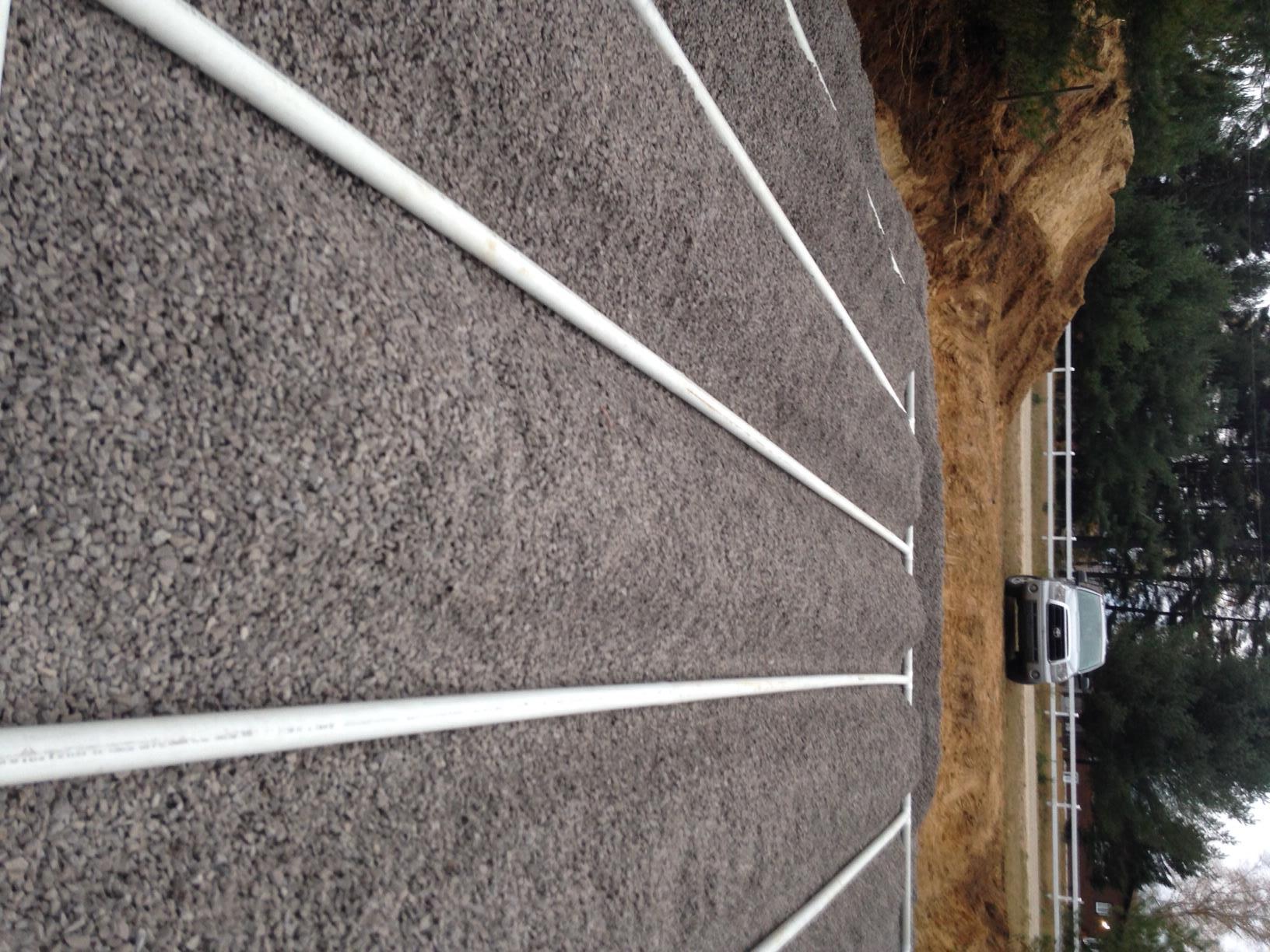Running track with white lane lines; car and trees in background.