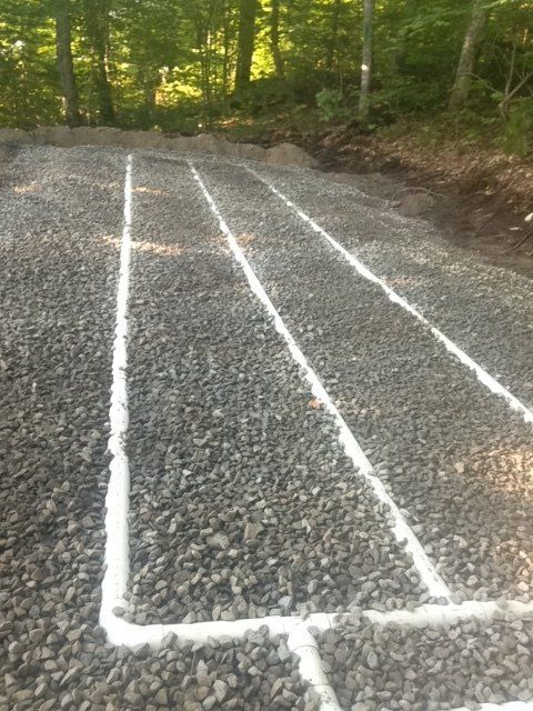 Une route de gravier avec des lignes blanches et des arbres en arrière-plan.