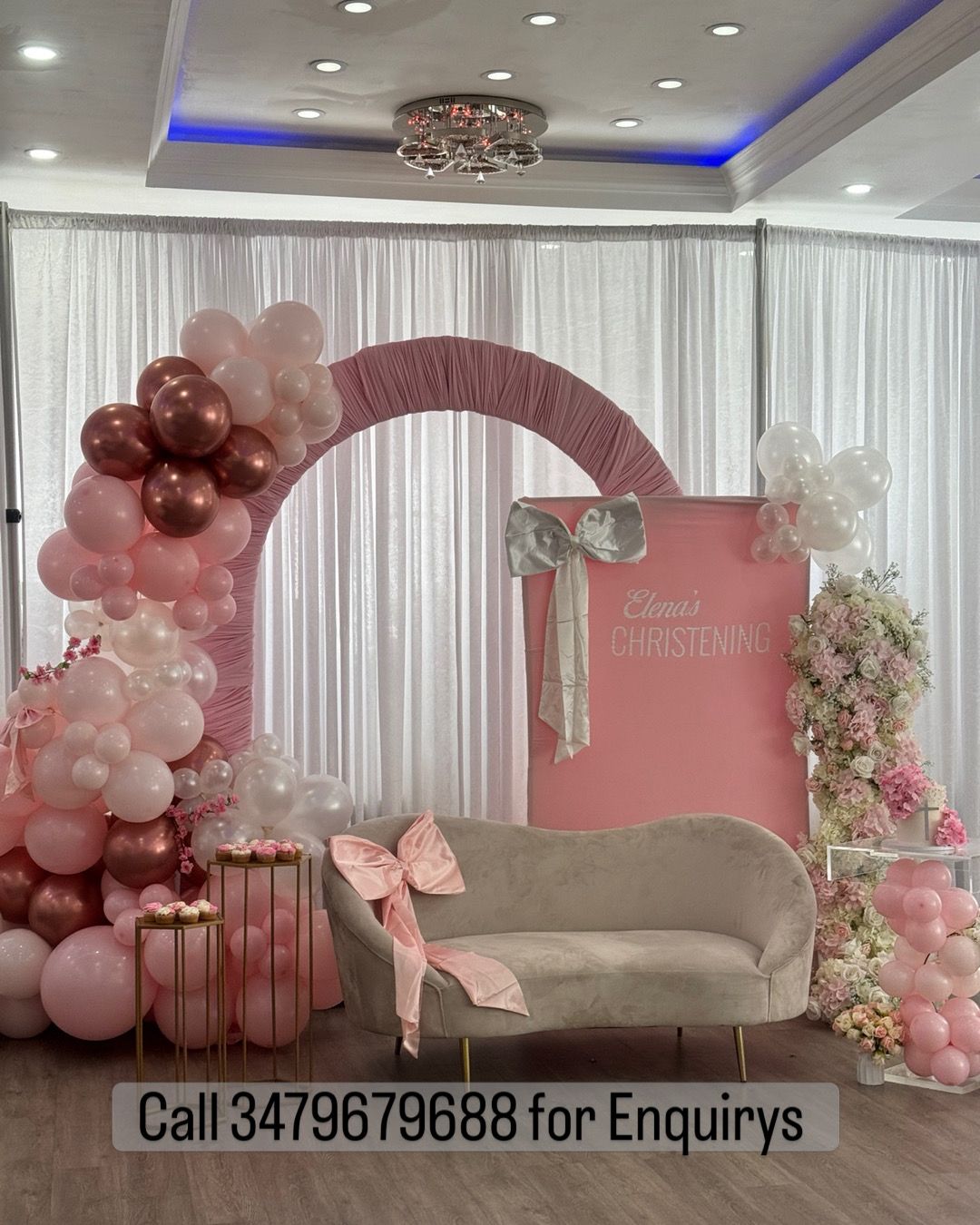Pink balloon arch and floral stage setup with couch, gift boxes, and “Call 3479679688 for Enquiries” sign