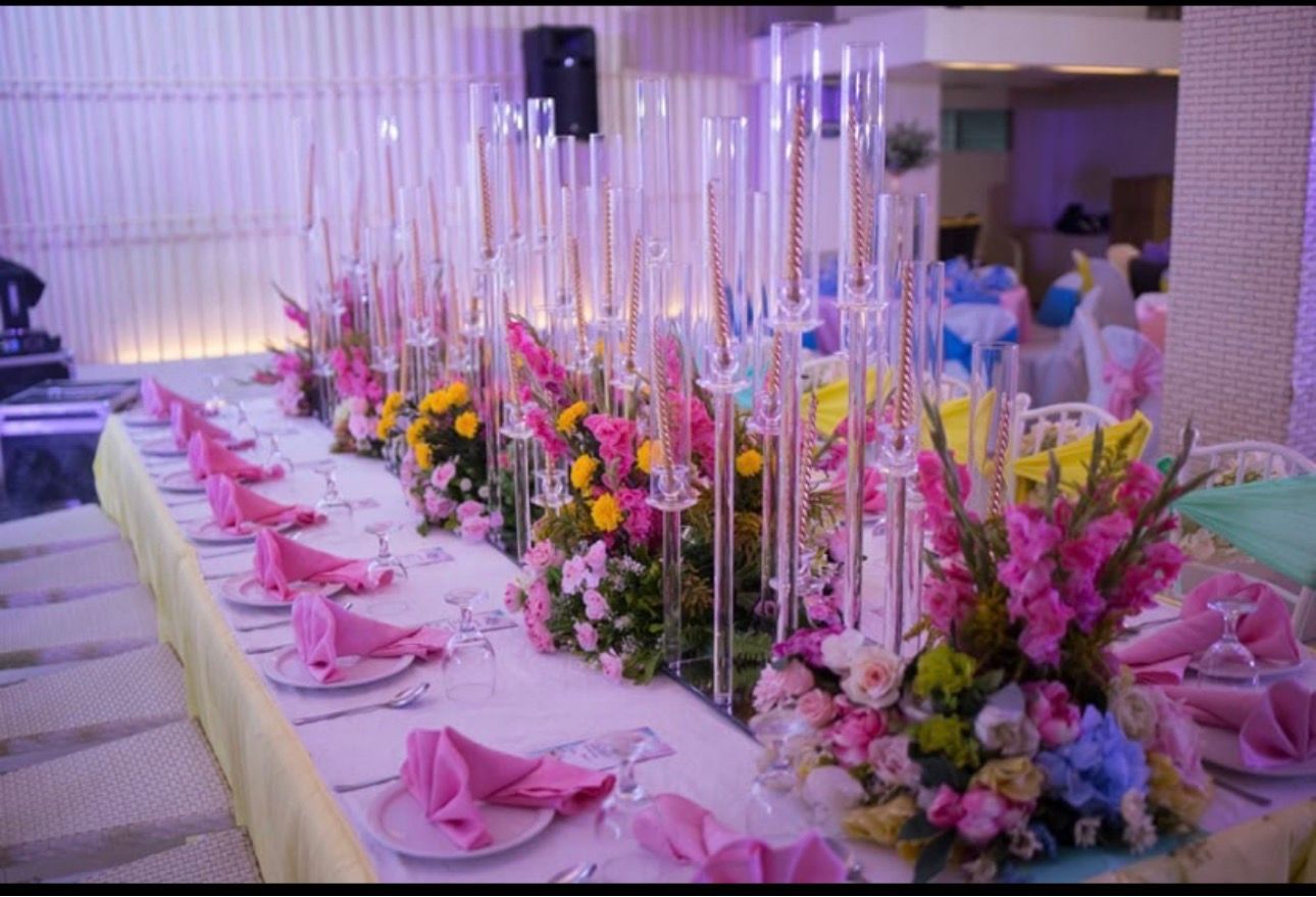 Decorated banquet table with pink napkins, floral centerpieces, and tall candles at a formal event