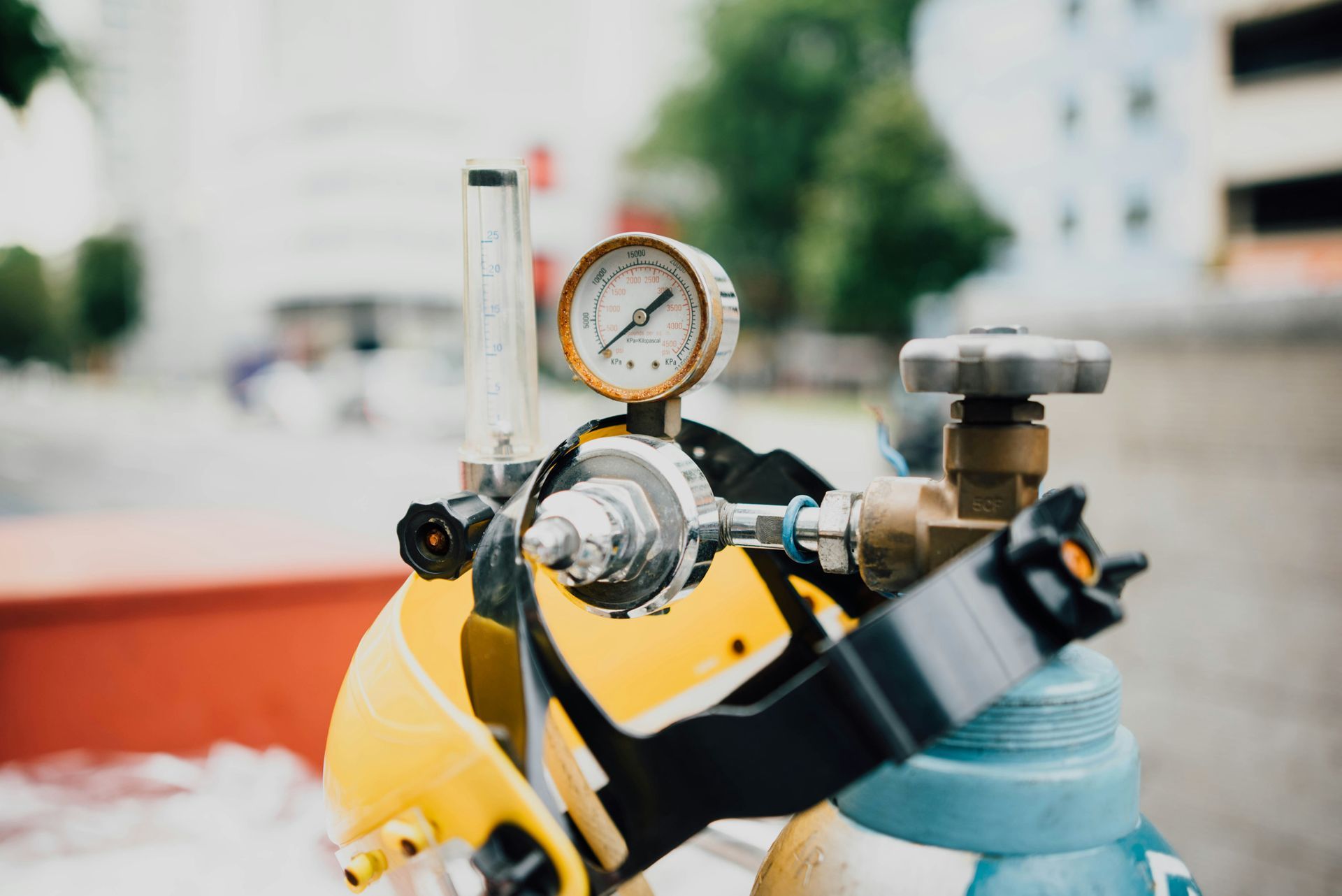 Yellow scuba tank with pressure gauge and regulator in the foreground outdoors