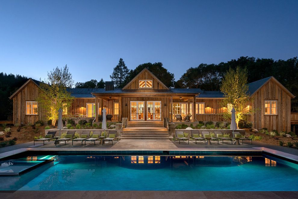 Wooden lodge at dusk with lit windows and a turquoise pool in front