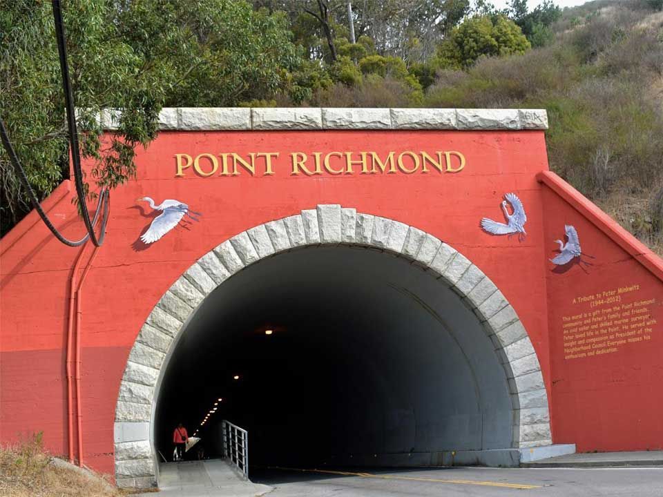 Point Richmond tunnel entrance with red facade and stone arch under trees