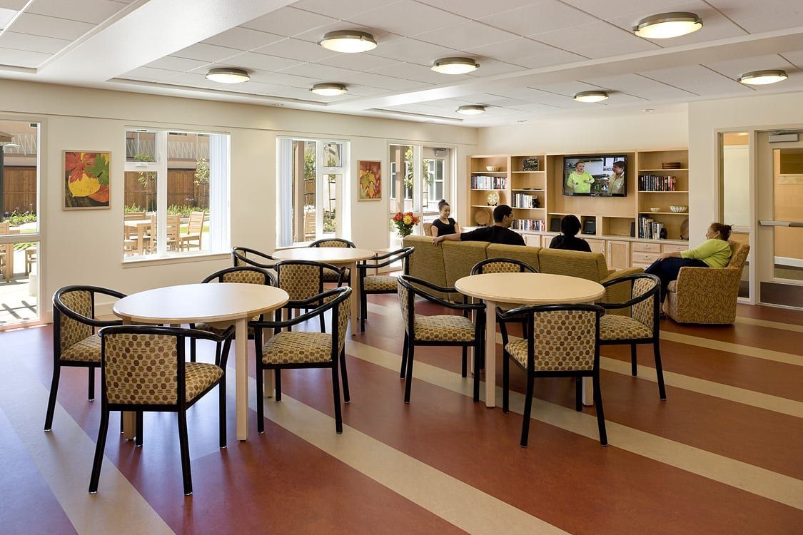 Bright hotel lounge with tables, wicker chairs, sofas, and large windows under recessed ceiling lights