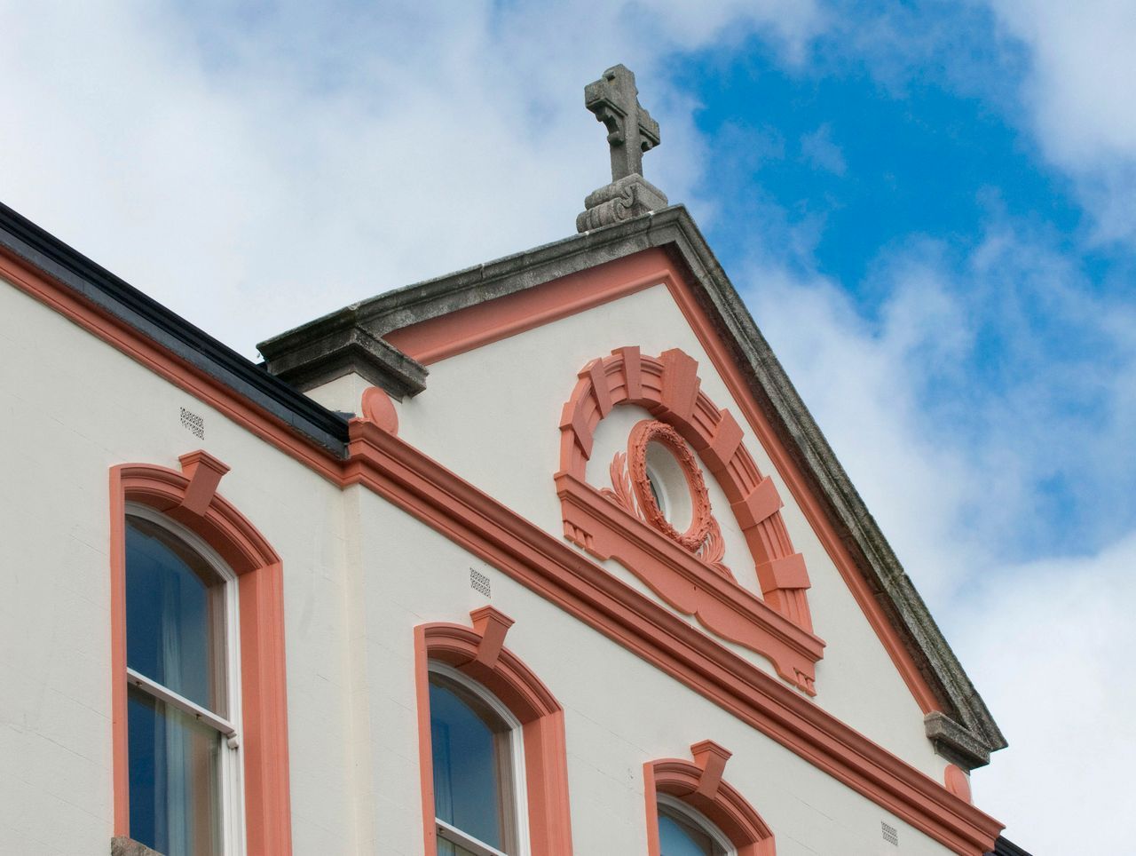 Red and white building facade with arched windows and a statue on the roofline