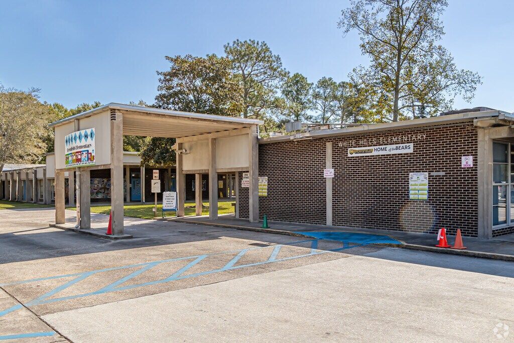 School building with a covered entrance, mural wall, and blue-marked parking spaces in front
