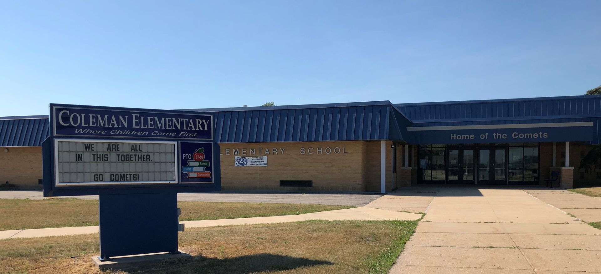 Coleman Elementary School building with front sign and walkway on a sunny day