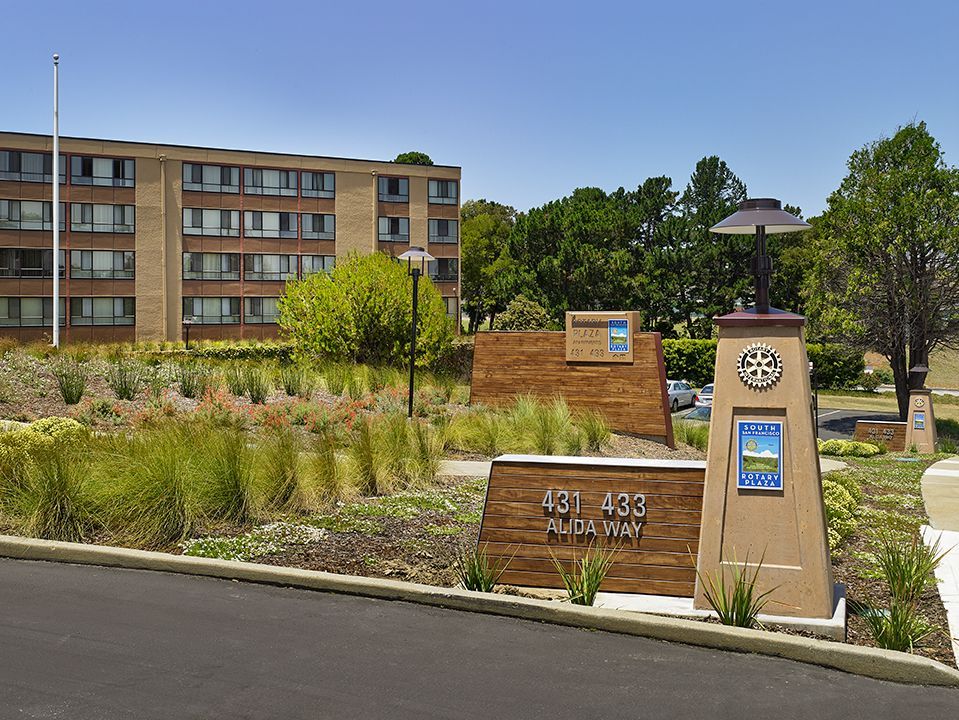 Apartment entrance sign and landscaped grounds with a building in the background