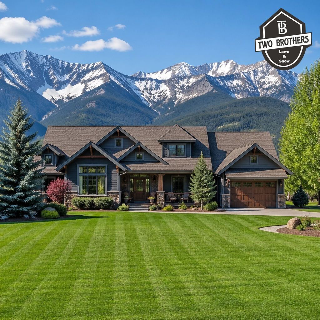 Modern house with large green lawn and snowcapped mountains in the background