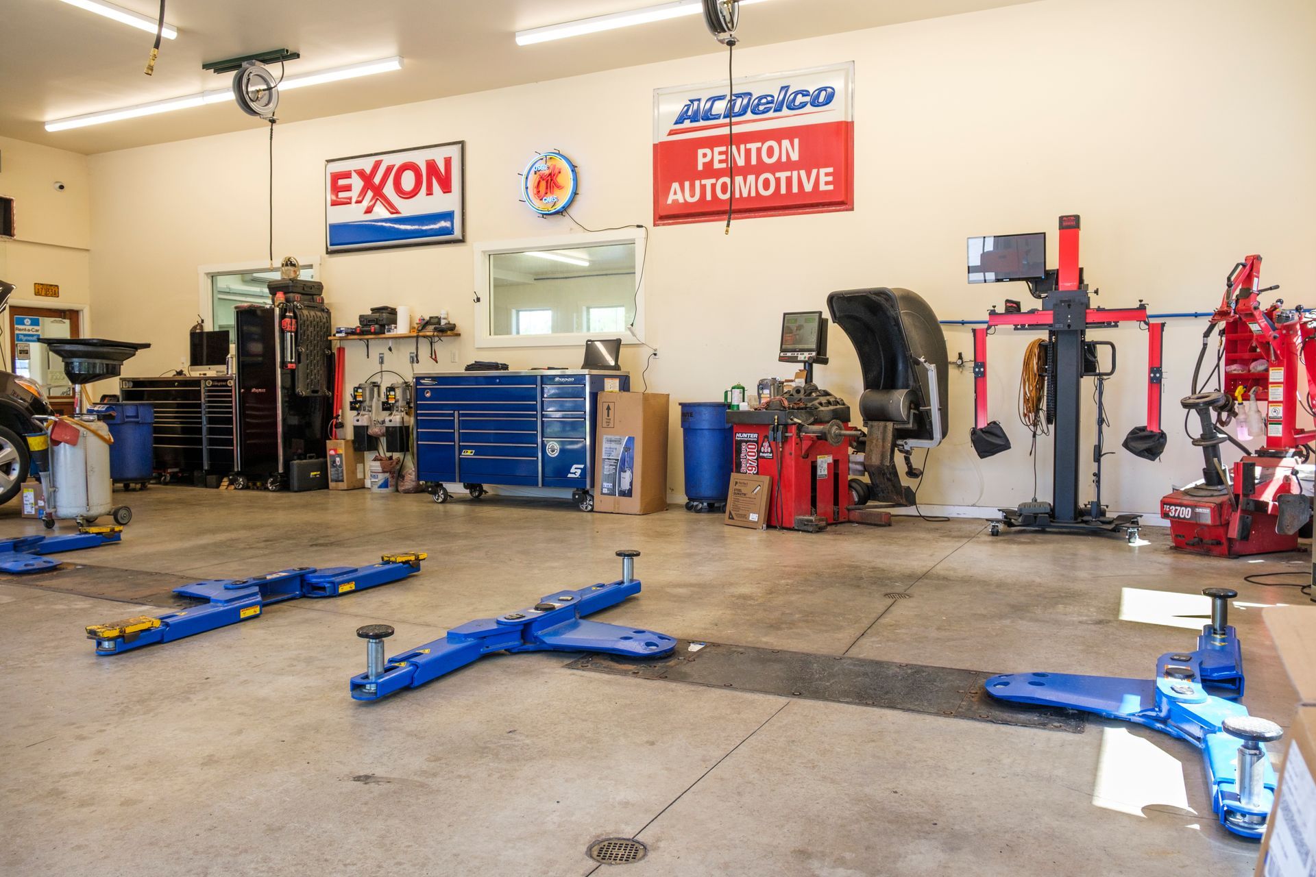 Garage interior with car lifts, tools, and signage for Exxon and AC Delco. | Boalsburg Car Co.
