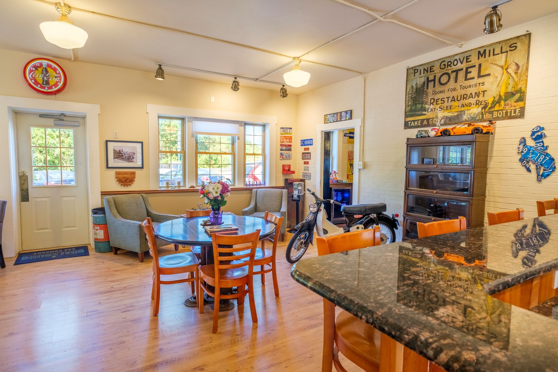 Interior with round table, chairs, seating, and vintage decor; exposed brick and a bar. | Boalsburg Car Co.