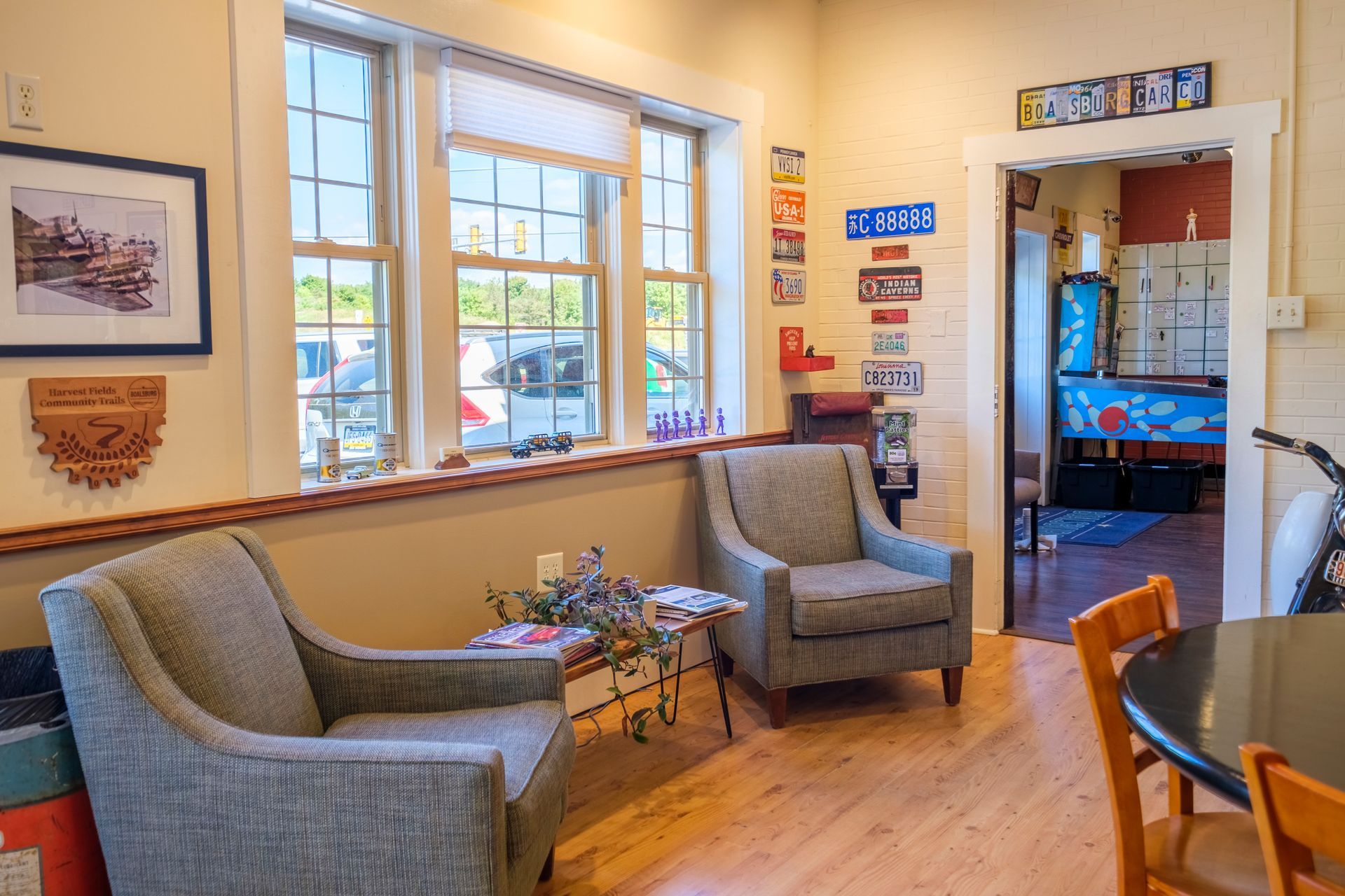 Cozy room with two armchairs near a window. Colorful signs adorn the doorway. | Boalsburg Car Co.