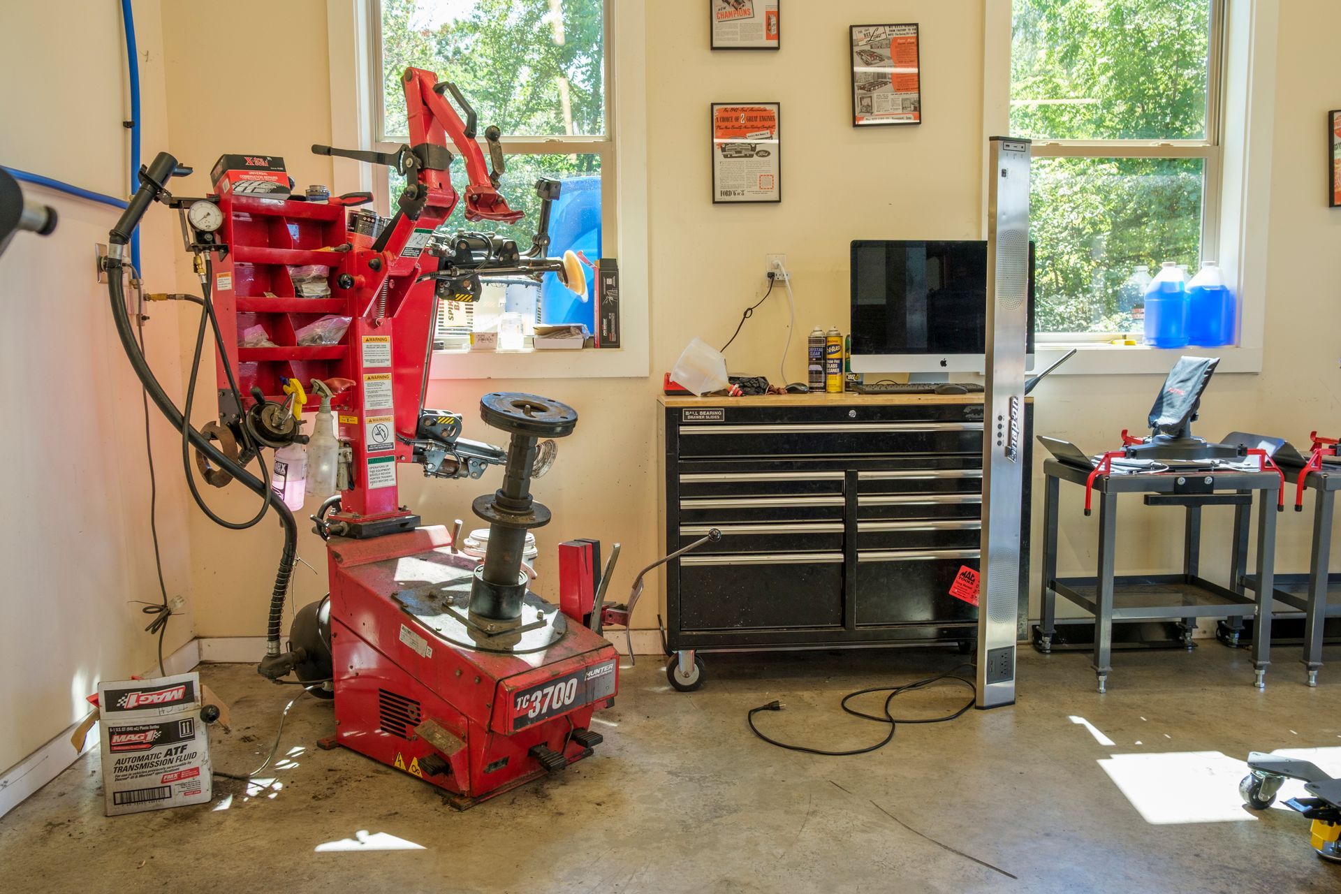 Red tire machine in garage with black toolbox, computer, and windows. | Boalsburg Car Co.