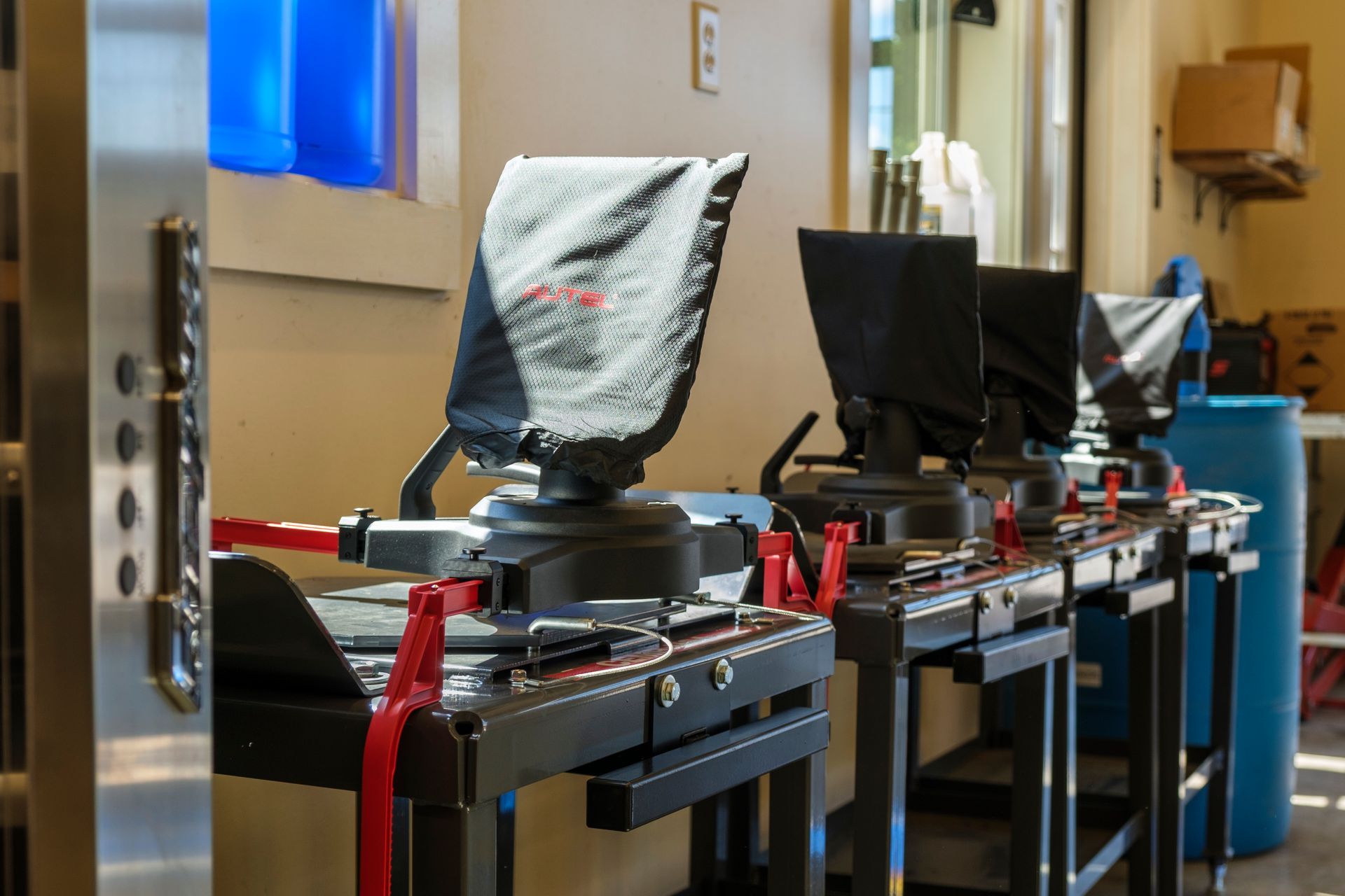 Voting machines lined up in a room with sunlight streaming in, secured by red straps. | Boalsburg Car Co.