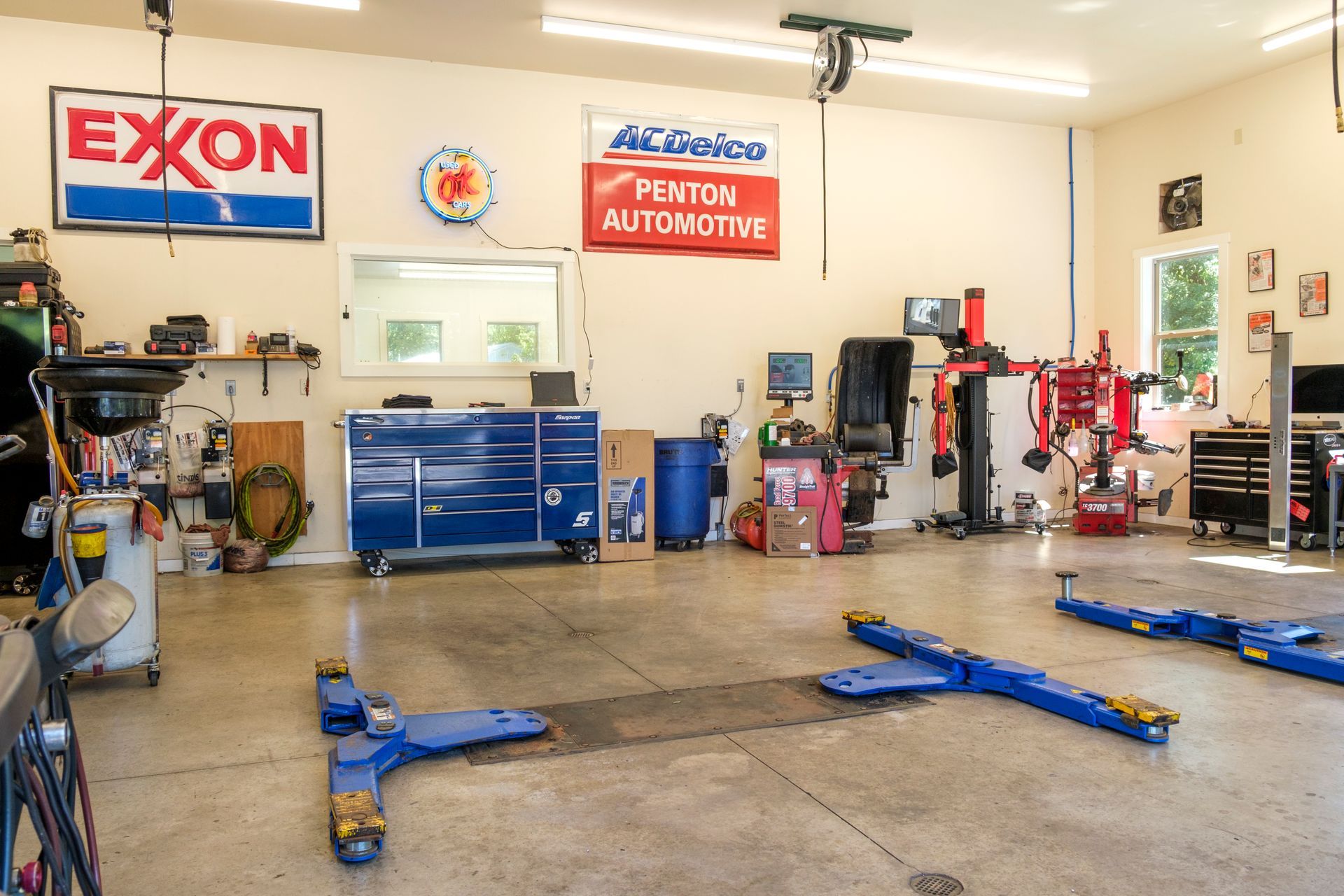 Garage interior with car lift, tools, and signs for Exxon and AC Delco. | Boalsburg Car Co.