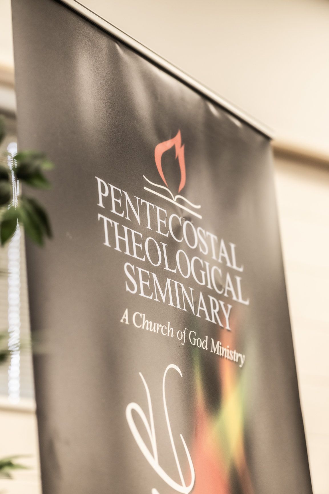 A banner for the pentecostal theological seminary is hanging on a wall.