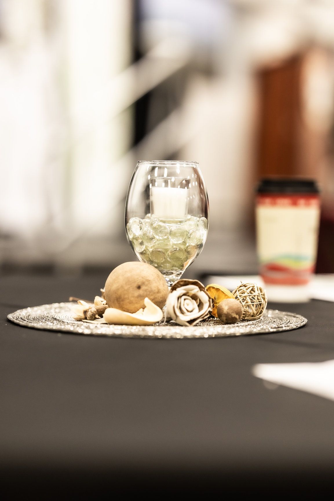 A table with a candle in a glass and seashells on it.