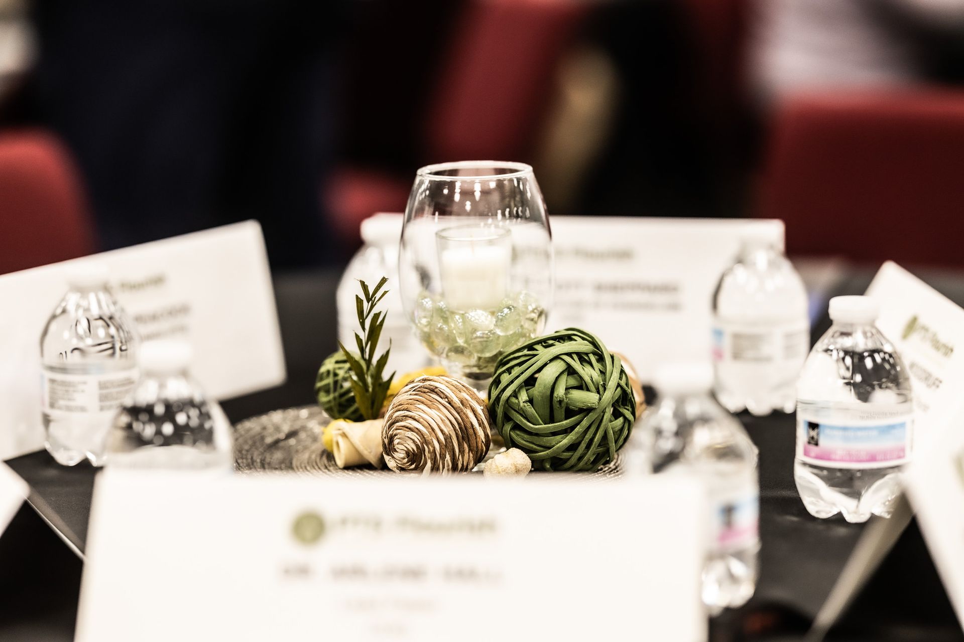 A table with a vase , bottles of water , and a sign on it.