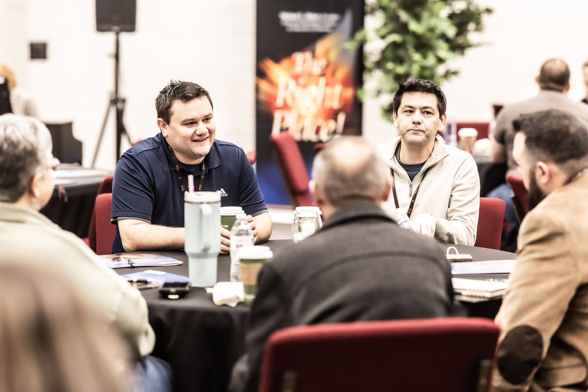 A group of men are sitting around a table talking.
