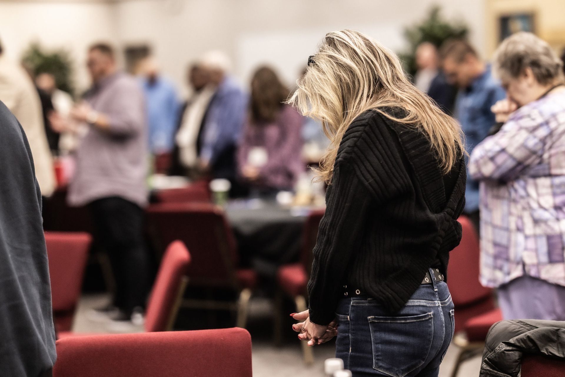 A woman is praying in front of a crowd of people in a church.