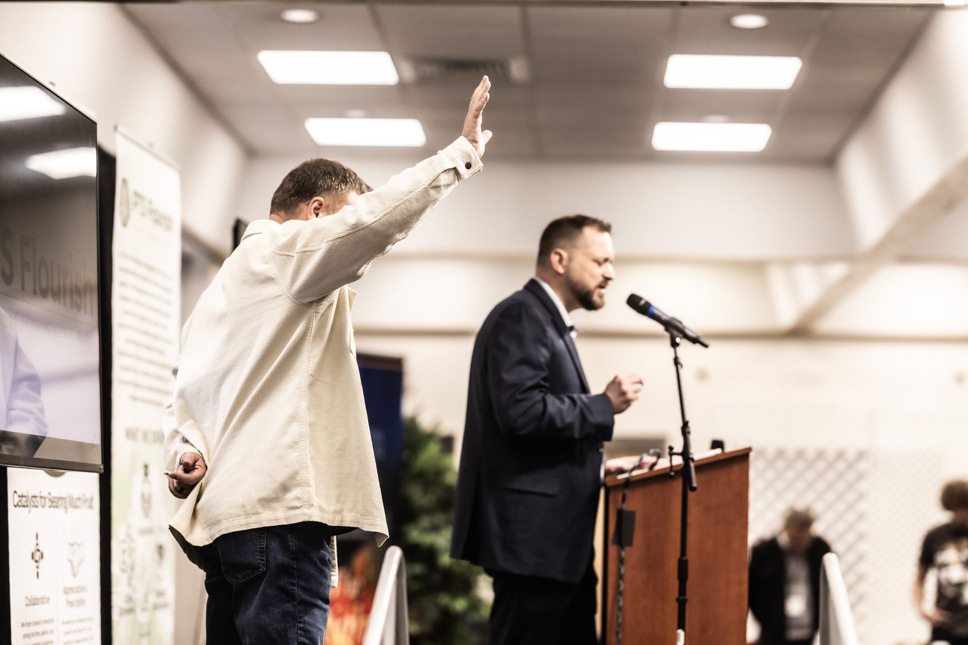 Two men are standing in front of a microphone in a room.