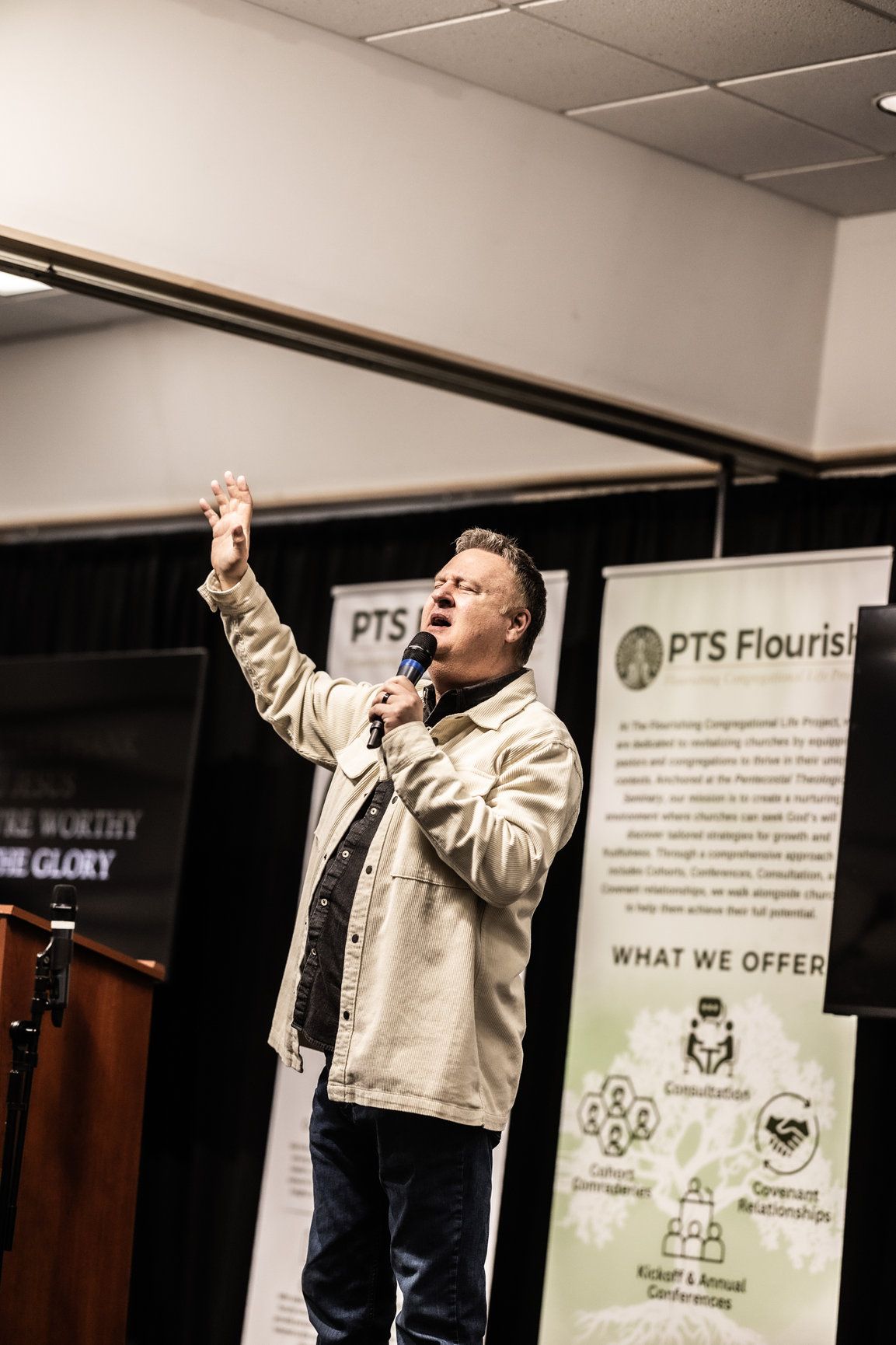 A man is standing in front of a podium holding a microphone.