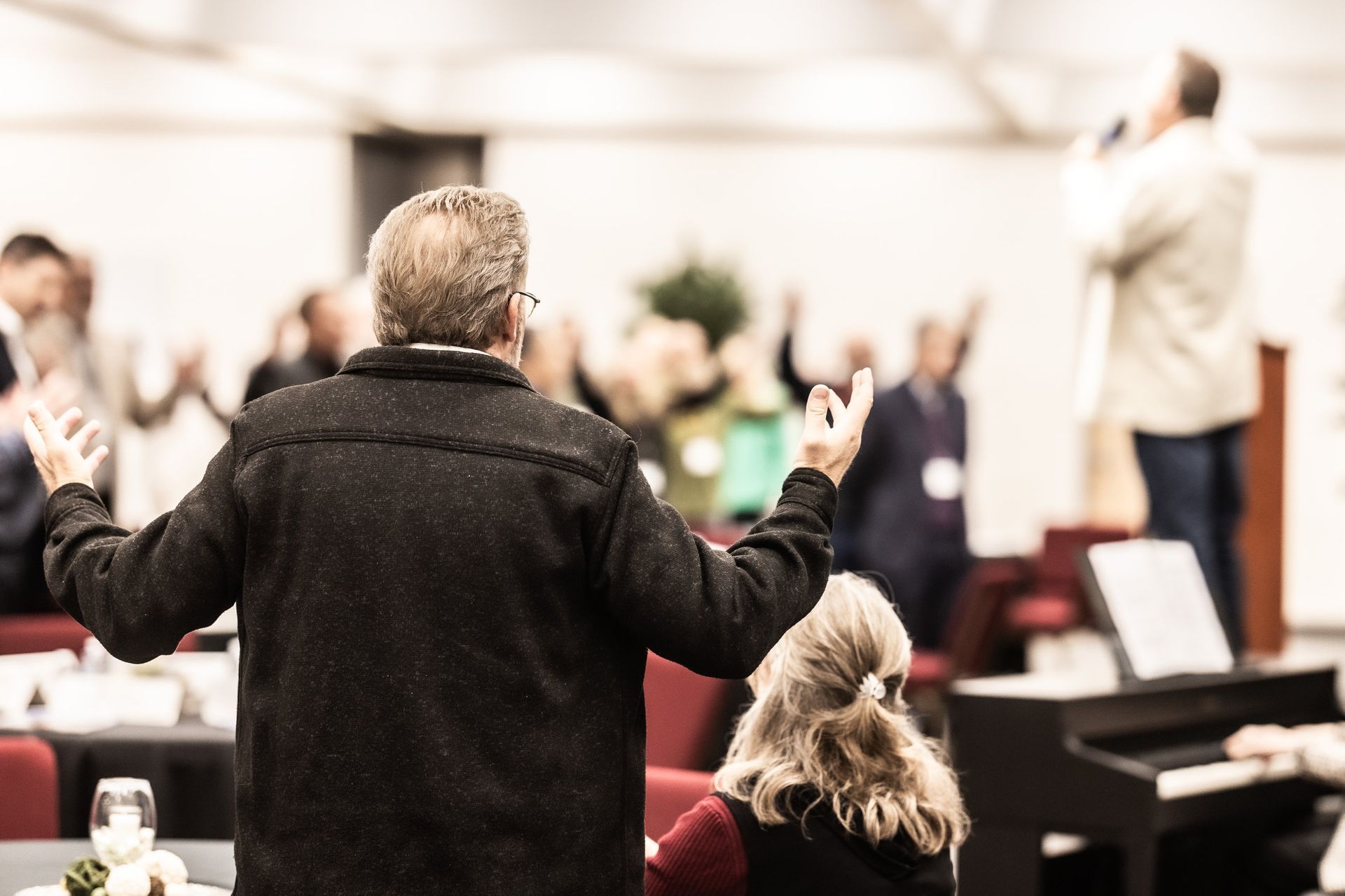 A man is standing in front of a crowd with his arms outstretched.