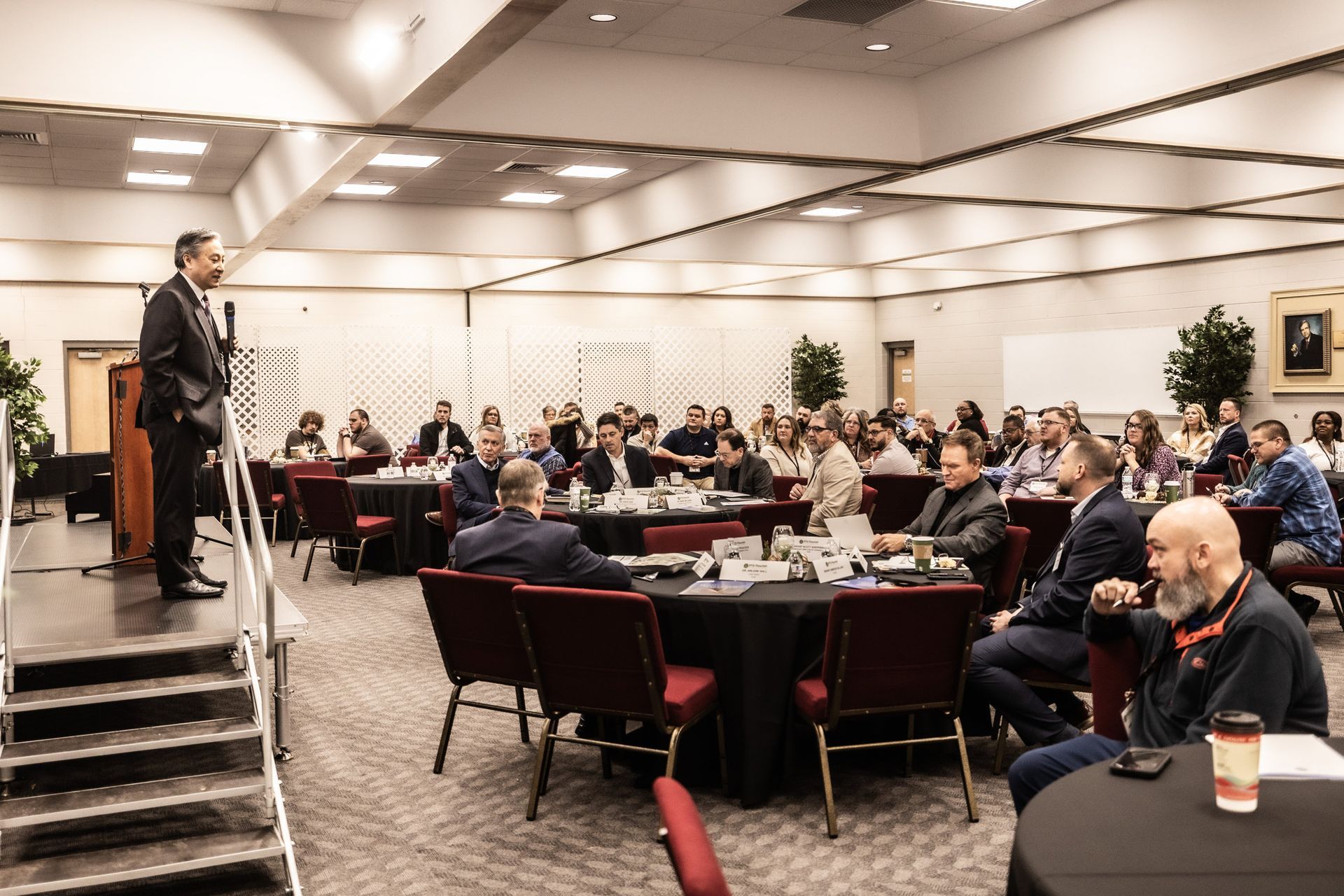A man is giving a presentation to a large group of people in a conference room.